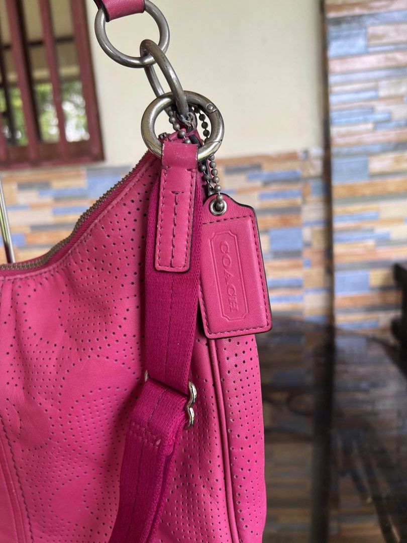 Coach Pink Perforated Leather Shoulder Bag (Category: Luxury Bags & Wallets) located in Iba. Submitted by saploot (Listing ID 1469114976, Image 2). Description: Bright pink Coach shoulder bag with perforated design throughout. Front round metal logo plate reads Coach Est. 1941. Fabric strap with adjustable buckle, matching leather hangtag attached to hardware rings. Zip top closure. Silver-tone hardware..
