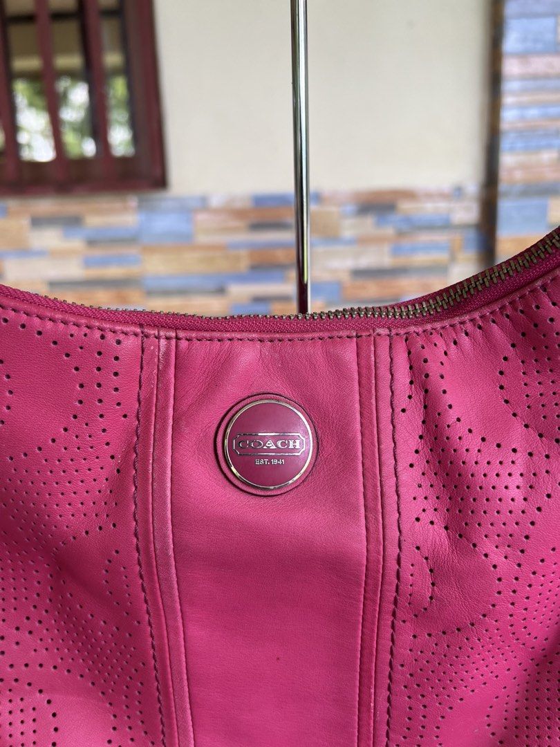 Coach Pink Perforated Leather Shoulder Bag (Category: Luxury Bags & Wallets) located in Iba. Submitted by saploot (Listing ID 1469114976, Image 3). Description: Bright pink Coach shoulder bag with perforated design throughout. Front round metal logo plate reads Coach Est. 1941. Fabric strap with adjustable buckle, matching leather hangtag attached to hardware rings. Zip top closure. Silver-tone hardware..