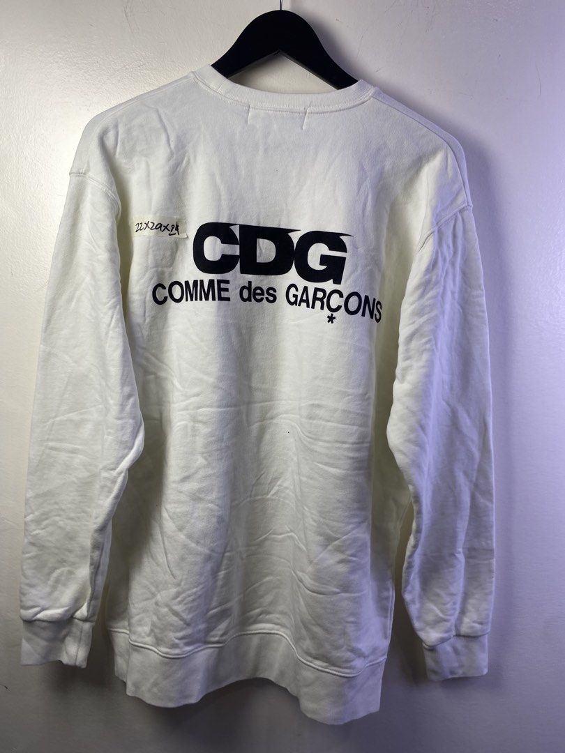 COMME des GARÇONS CDG White Sweatshirt XXL (Category: Coats, Jackets and Outerwear) located in Manila. Submitted by declutterpromax (Listing ID 1468997470, Image 3). Description: - Brand: Comme des Garçons (CDG) - Color: White with bold black back logo and star symbol - Size: XXL - Style: Classic crewneck, ribbed cuffs and hem - Condition: Clean look, easy to style with denim or joggers - Measurements: Provided in the photos.