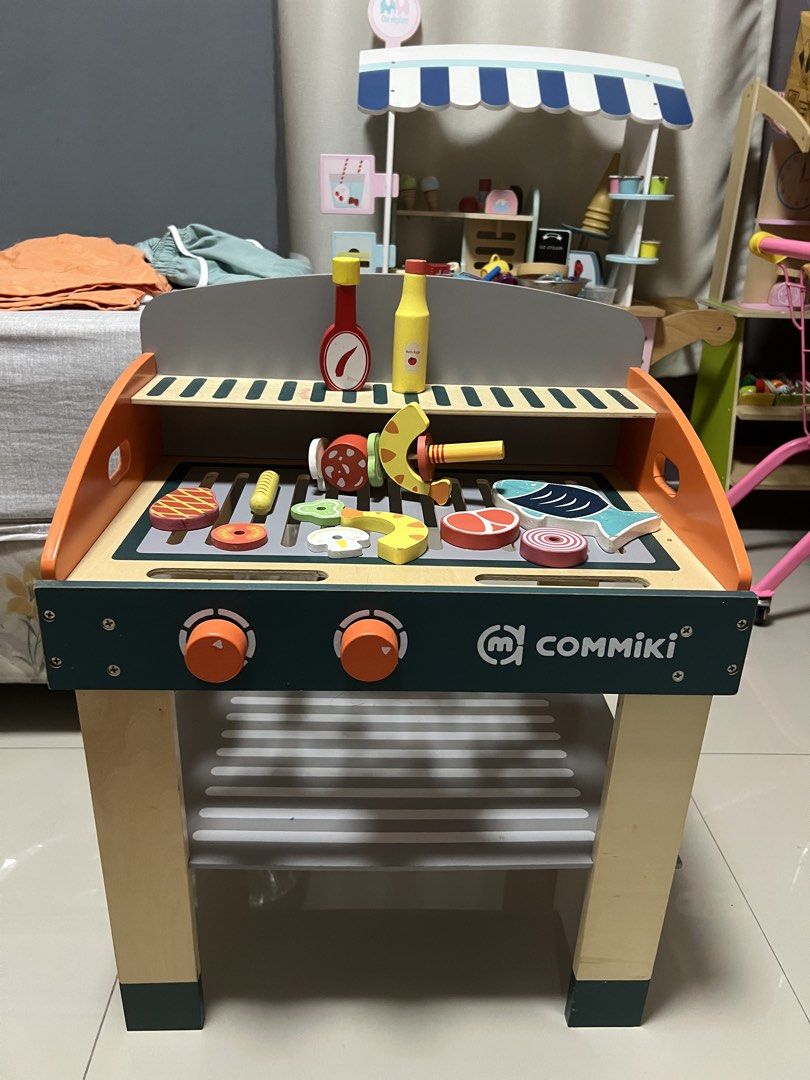 Commiki Wooden BBQ Grill Toy Set (Category: Kids Toys) located in Paranaque City. Submitted by heyoli (Listing ID 1469013780, Image 1). Description: - Brand: Commiki - Type: Wooden play barbecue set - Features interactive turning dials and a convenient storage shelf underneath - Includes magnetic play food (steak, fish, sausage, veggies) and condiment bottles - Great for engaging pretend play and developing fine motor skills.