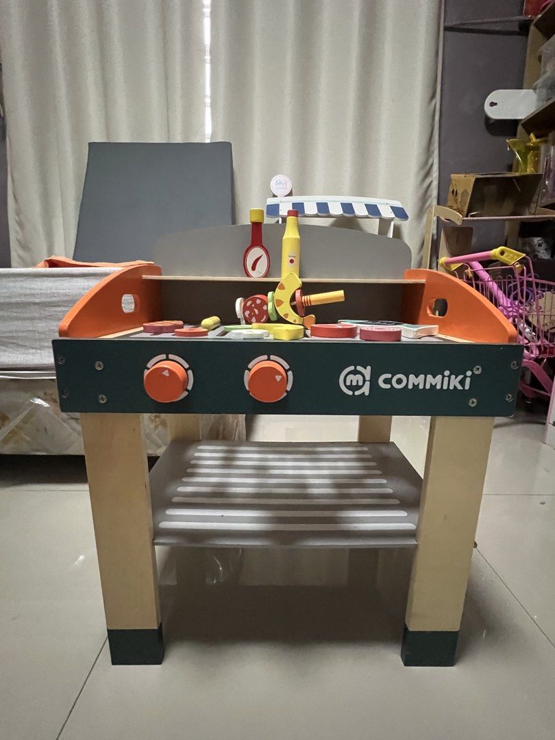 Commiki Wooden BBQ Grill Toy Set (Category: Kids Toys) located in Paranaque City. Submitted by heyoli (Listing ID 1469013780, Image 3). Description: - Brand: Commiki - Type: Wooden play barbecue set - Features interactive turning dials and a convenient storage shelf underneath - Includes magnetic play food (steak, fish, sausage, veggies) and condiment bottles - Great for engaging pretend play and developing fine motor skills.