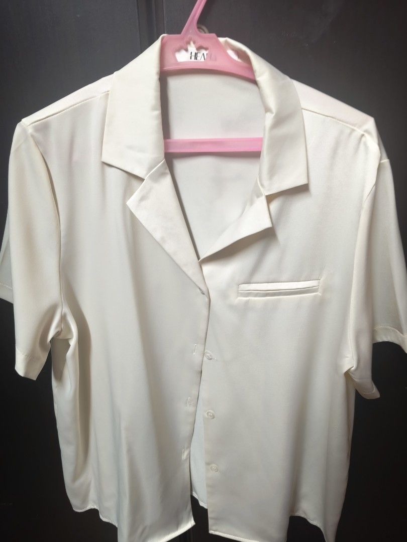 Cream Silk Short Sleeve Button Down Shirt (Category: Shirts) located in Quezon City. Submitted by ng.stephanielauren (Listing ID 1469108312, Image 1). Description: - Color: Cream (Neutral tone that matches everything) - Style: Short sleeve button-down with lapel collar and chest pocket - Fit: Regular fit - Material: Smooth satin-like fabric - Season: Great casual piece for warm weather - Condition: Clean and ready to wear.