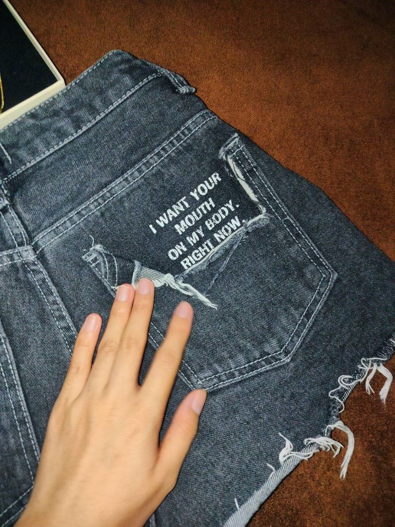Denim shorts with raw hem and text graphic (Category: Shorts) located in Las Pinas. Submitted by alkwinuts (Listing ID 1469159856, Image 2). Description: - Style: High-waisted black washed denim shorts with an edgy vibe - Closure: Classic button fly - Details: Raw frayed hems and back pocket graphic text reading 'I want your mouth on my body right now.' - Pockets: Functional front and back pockets - Versatility: Great for casual day wear or styli