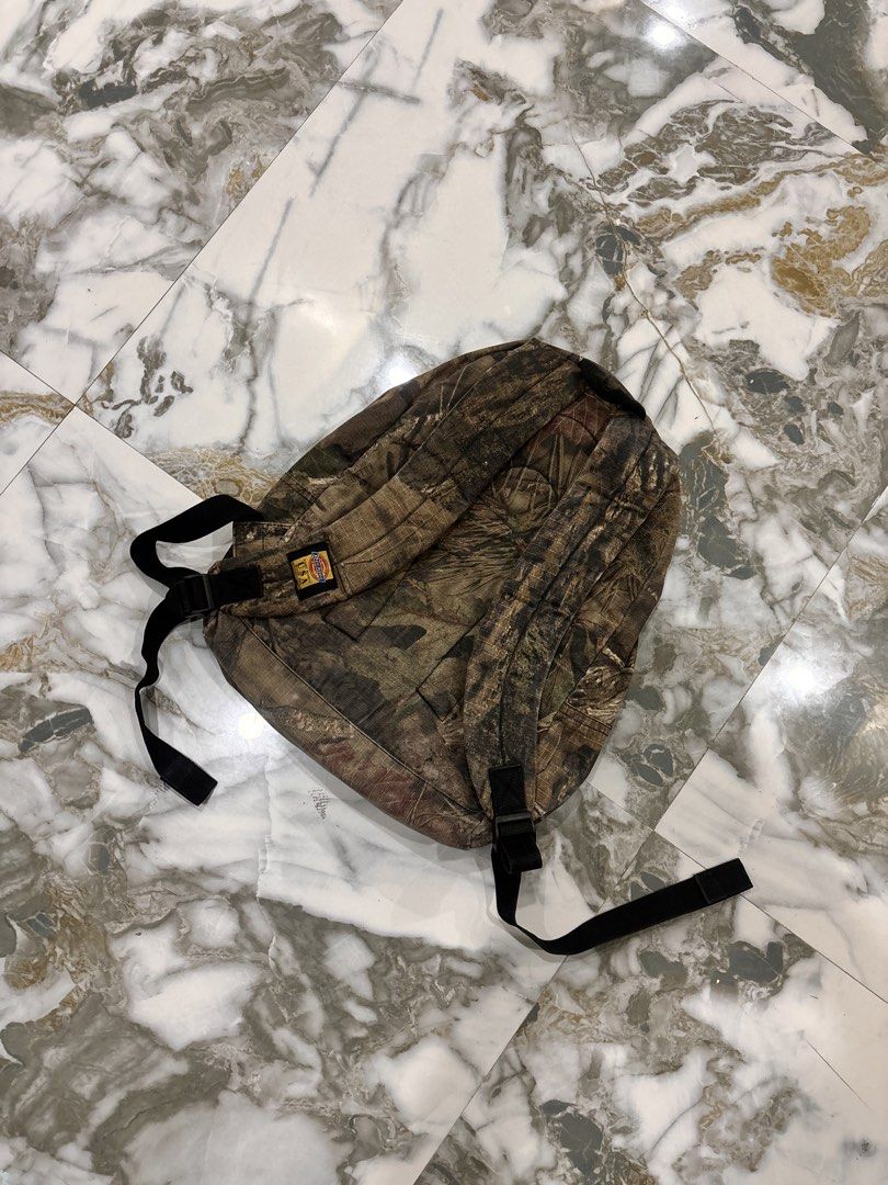 Dickies Mossy Oak Camo Backpack (Category: Backpacks) located in Cavite. Submitted by gelloots (Listing ID 1469047013, Image 2). Description: - Brand: Dickies - Pattern: Mossy Oak Camouflage - Storage: Classic front zip pocket for quick access - Details: Custom branded metal zipper pulls and iconic red Dickies logo patch - Comfort: Adjustable shoulder straps and padded backing - Condition: Great everyday carry for school, work, or outdoor trips.