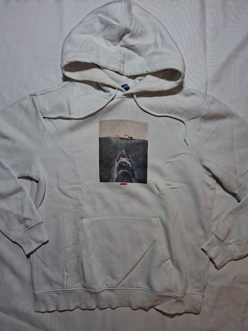 Divided Jaws Graphic Hoodie White Size M (Category: Hoodies) located in Baguio. Submitted by restyrille77846 (Listing ID 1469155067, Image 1). Description: - Brand: Divided - Color: White - Size: Medium (Length: ~26 inches) - Design: Jaws graphic on front with 'YOU'RE GONNA NEED A BIGGER BOAT' on the back - Features: Kangaroo pocket and adjustable drawstring hood - Origin: Made in Cambodia - Condition: Great find, perfect for casual wear.