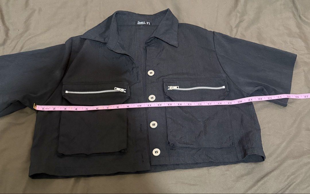 Double D Black Button-Up Shirt with Utility Pockets (Category: Shirts) located in Quezon City. Submitted by turtleandfishes (Listing ID 1468933834, Image 2). Description: - Brand: Double D - Color: Black - Style: Utility short-sleeve button-up shirt with collared neckline and silver metal hardware - Details: Two large front pockets with zipper accents on the flaps, lightweight crinkled texture fabric - Measurements: Pit-to-pit approx. 22.5", Tota