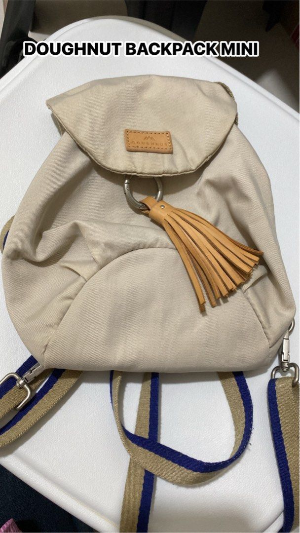 Doughnut Backpack Mini (Category: Backpacks) located in Silang. Submitted by princess_jasmin (Listing ID 1469104933, Image 1). Description: - Brand: Doughnut - Colorway: Cream canvas with tan leather details - Closure: Front flap with metal ring and matching leather tassel - Straps: Tan and blue striped adjustable shoulder straps with silver hardware - Style: Compact and perfect for daily casual carry - Condition: Excellent / Well-maintained - Sh