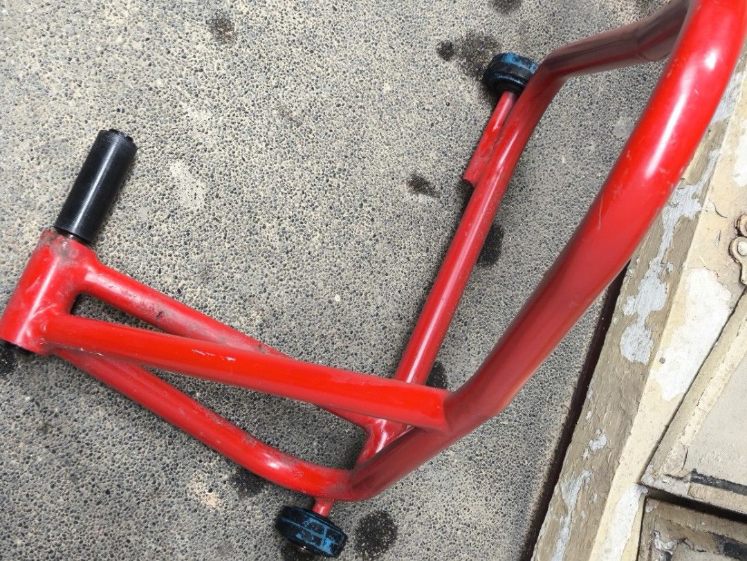 Ducati Motorcycle Rear Paddock Stand (Category: Bicycles) located in Pasig City. Submitted by giarpo (Listing ID 1469056674, Image 3). Description: - Red steel rear paddock stand for motorcycles - Measures ~21 cm across the lifting pin - Sturdy build with small black wheels for easy rolling - Shows minor scuffs and paint chips from normal workshop use - 100% solid and fully functional for maintenance and chain cleaning.
