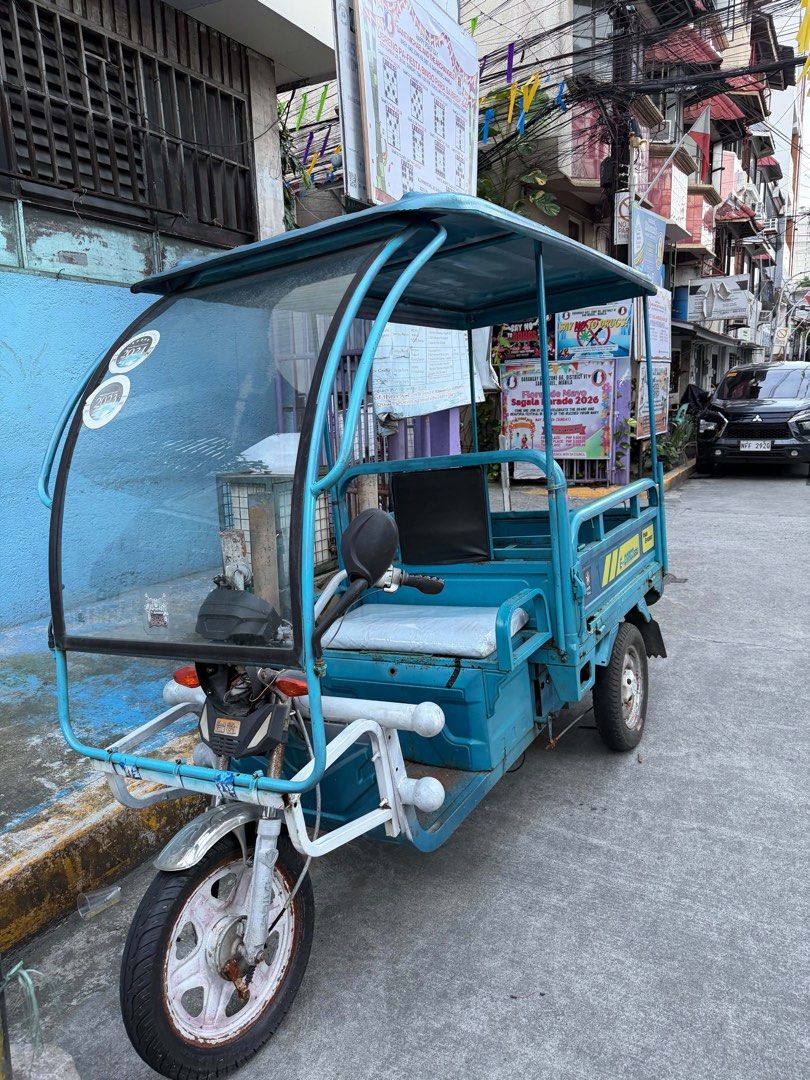 E-Cargo 650J Electric Tricycle Blue (Category: Motorbikes for Sale) located in Manila. Submitted by alendlr (Listing ID 1468974786, Image 2). Description: Battery need replacement Headlight not working No switch See UNIT in person. Blue utility electric tricycle, model E-Cargo 650J. Fitted with a covered roof, front windshield, front passenger seat, and a rear cargo bed with drop-down side panels. Powered transport for deliveries or passenger hau