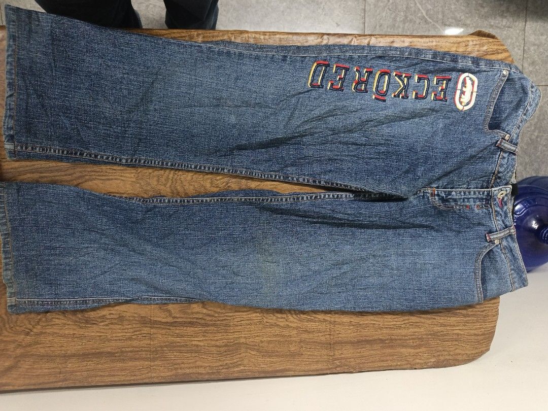 Ecko Red embroidered denim jeans (Category: Jeans) located in Manila. Submitted by criss_11 (Listing ID 1469102748, Image 1). Description: - Vintage Ecko Red denim jeans in a classic blue wash - Large embroidered lettering and iconic rhino logo down the right leg - Unique red contrast stitching on back pockets over dark wash details - Mid-rise fit with standard button and zipper fly - Perfect throwback piece for an authentic Y2K streetwear look.