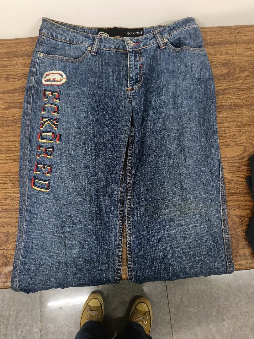 Ecko Red embroidered denim jeans (Category: Jeans) located in Manila. Submitted by criss_11 (Listing ID 1469102748, Image 3). Description: - Vintage Ecko Red denim jeans in a classic blue wash - Large embroidered lettering and iconic rhino logo down the right leg - Unique red contrast stitching on back pockets over dark wash details - Mid-rise fit with standard button and zipper fly - Perfect throwback piece for an authentic Y2K streetwear look.