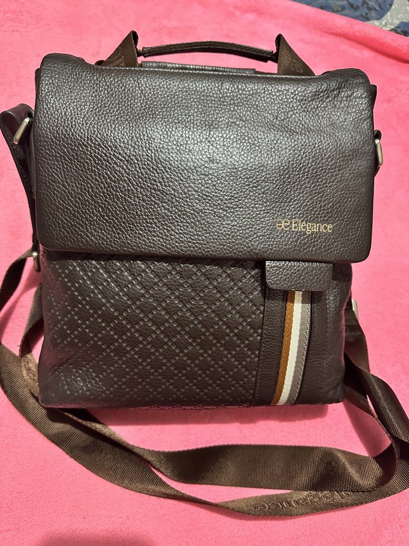 Elegance brown leather messenger bag (Category: Sling Bags) located in Quezon City. Submitted by pongoy (Listing ID 1469008089, Image 2). Description: - Brand: Elegance - Material: Brown leather in a deep brown colorway - Design: Textured geometric front panel with a vertical striped accent - Closure: Flap closure with a secure magnetic snap - Strap: Adjustable brown fabric shoulder strap featuring woven branding - Storage: Convenient back zipper