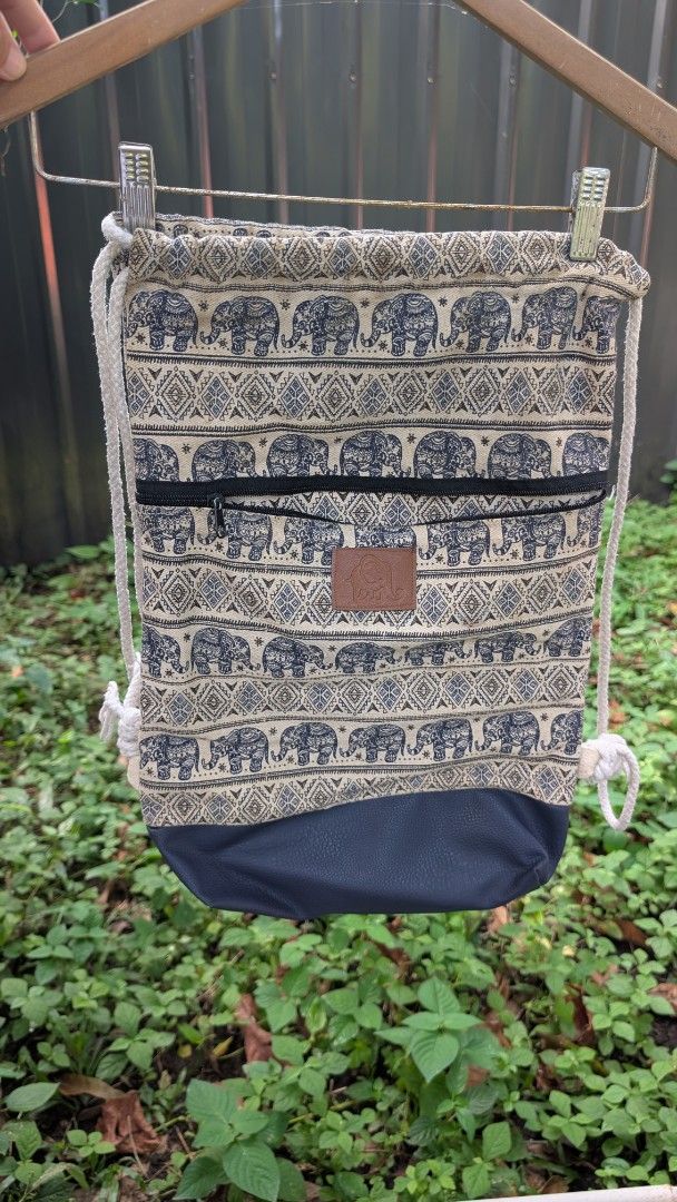 Elephant pattern drawstring backpack with faux leather base (Category: Backpacks) located in Manila. Submitted by alyssaapac81898 (Listing ID 1469000330, Image 1). Description: - Style: Boho drawstring backpack with eye-catching elephant and geometric patterns - Storage: Main compartment with secure rope closure plus a handy front zipped pocket - Durability: Features a stylish and sturdy navy blue faux leather bottom panel - Details: Finished wit