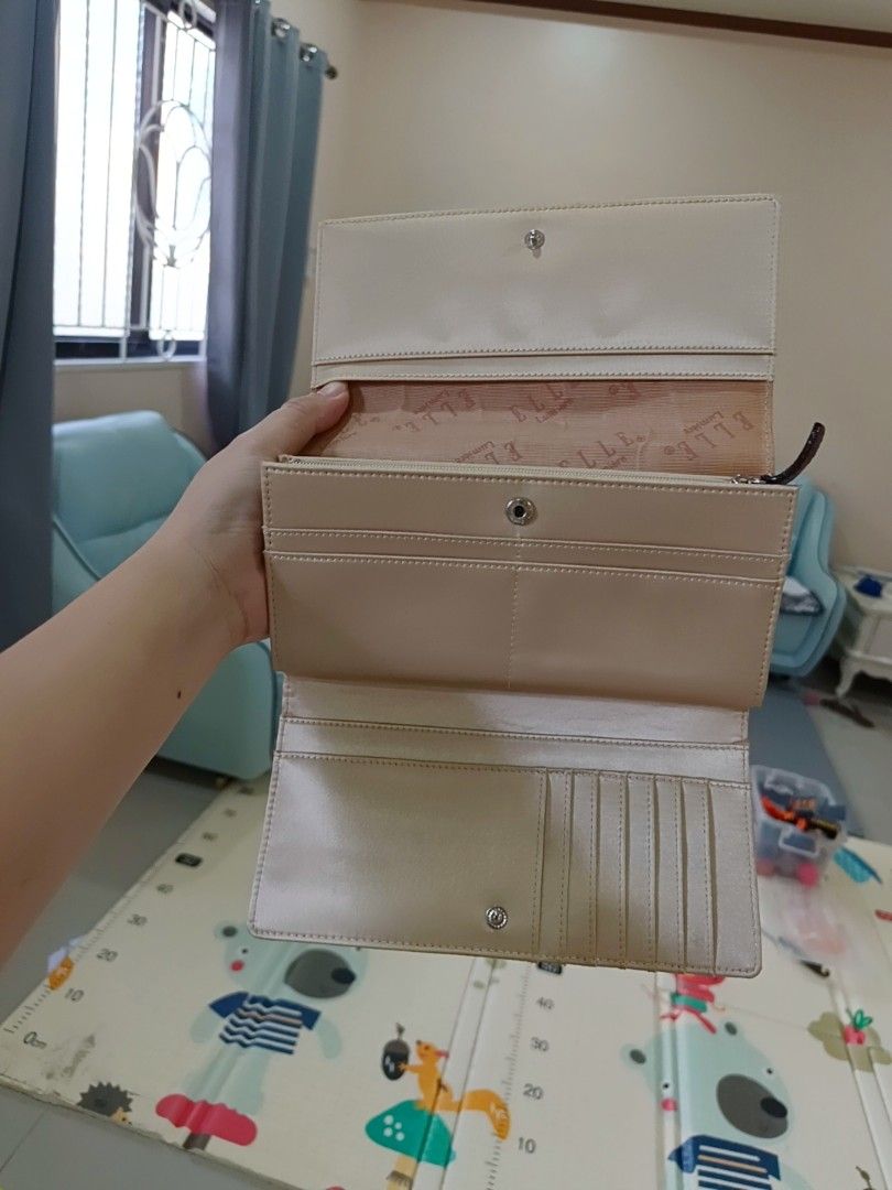 Elle Lumiere Beige Long Wallet (Category: Wallets & Card holders) located in Angeles City. Submitted by wanday_dreamer (Listing ID 1468983097, Image 2). Description: Elle Lumiere long wallet in beige. Snap button closure on the front flap. Inside has multiple card slots, bill compartments, and a zippered pocket. Branded fabric lining inside. Brown accent patch with the Elle logo on the outside. Clean interior and exterior, plenty of space for car