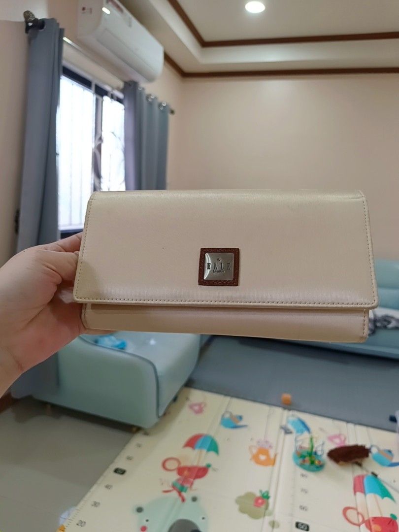 Elle Lumiere Beige Long Wallet (Category: Wallets & Card holders) located in Angeles City. Submitted by wanday_dreamer (Listing ID 1468983097, Image 1). Description: Elle Lumiere long wallet in beige. Snap button closure on the front flap. Inside has multiple card slots, bill compartments, and a zippered pocket. Branded fabric lining inside. Brown accent patch with the Elle logo on the outside. Clean interior and exterior, plenty of space for car