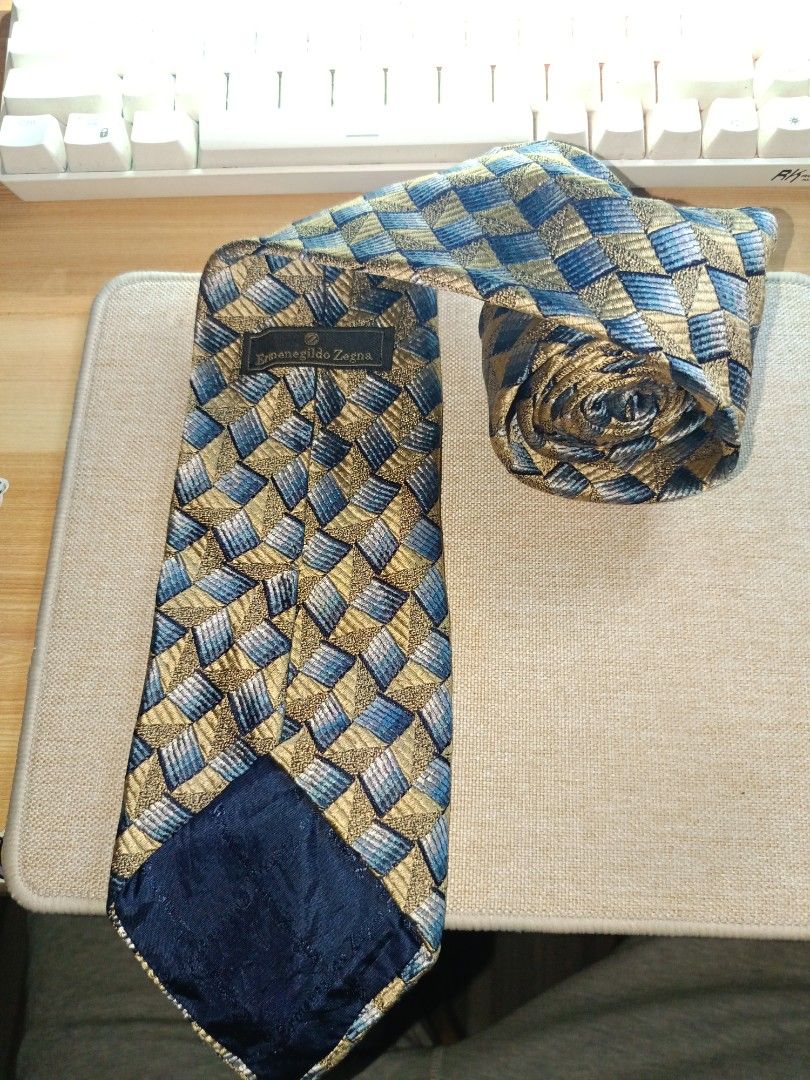 Ermenegildo Zegna Geometric Pattern Silk Tie (Category: Ties) located in Quezon City. Submitted by charlesfab66127 (Listing ID 1469086787, Image 2). Description: - Brand: Ermenegildo Zegna - Material: 100% High-quality Italian Silk - Design: Detailed geometric basketweave pattern in gold, blue, and grey tones - Features: Standard width blade, clean pointed tip, and branded fabric keeper loop - Ideal for: Formal events, weddings, and professional 