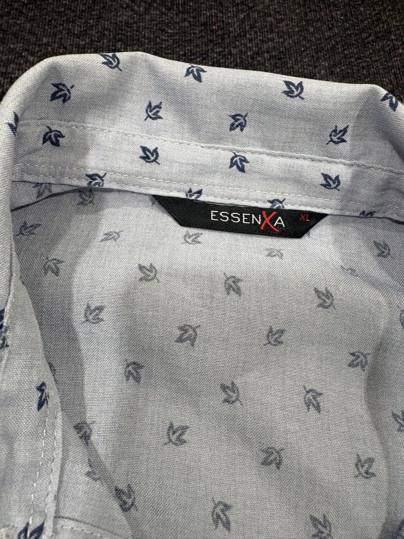 Essenxa A Light Blue Leaf Print Long Sleeve Shirt (Category: Longsleeves) located in Quezon City. Submitted by fast.closetfinds (Listing ID 1469013250, Image 2). Description: - Brand: Essenxa - Style: Long-sleeve button-down shirt with standard collar - Color/Pattern: Light blue with dark leaf pattern throughout - Details: Roll-up long sleeves with button tab detail - Size: XL - Material: Lightweight, comfortable fabric - Condition: Excellent, id