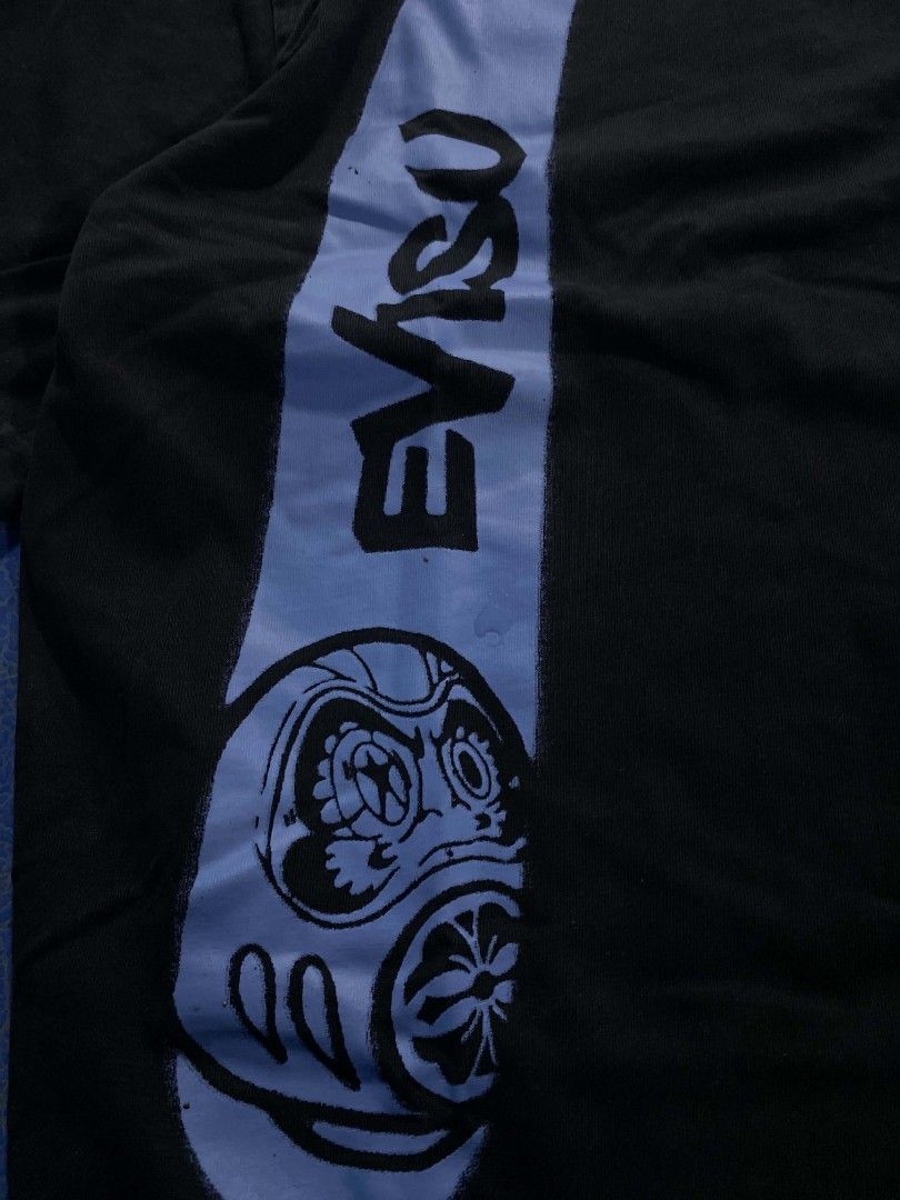 Evisu Black Graphic T-Shirt Size M (Category: Tshirts & Polo Shirts ) located in Manila. Submitted by jessieboym36298 (Listing ID 1468946727, Image 1). Description: - Brand: Evisu - Color: Black with light blue graphics - Size: Medium (M) - Fit: Regular fit, short sleeves - Design: Graffiti style logo on front chest, large signature print with Daruma mask detail on back - Condition: Clean fabric with bright, vibrant graphics - Style: Streetwear /