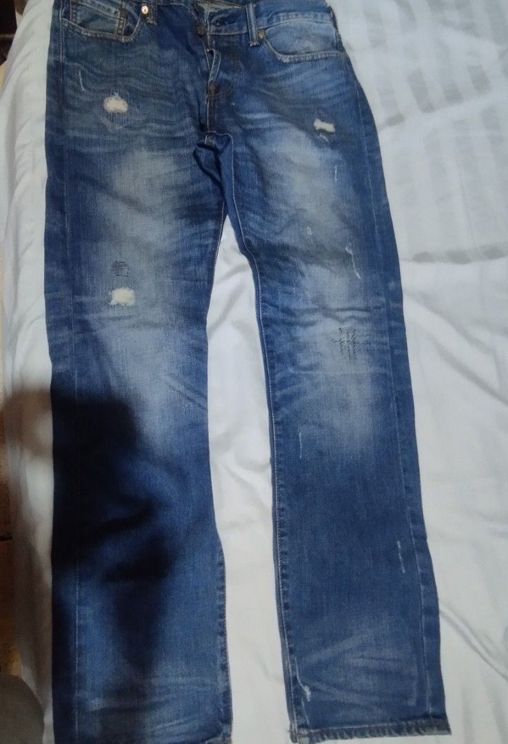 Evisu Blue Distressed Denim Jeans (Category: Jeans) located in Manila. Submitted by lene48 (Listing ID 1468937752, Image 1). Description: - Brand: Evisu - Color/Wash: Blue faded wash with distressed and patched details - Fit: Regular fit, straight leg cut - Closure: Classic button fly - Unique Design: Painted blue graphics with fish skeleton on back pockets - Branded Details: Inside waistband text, printed pocket lining, and back leather patch - 
