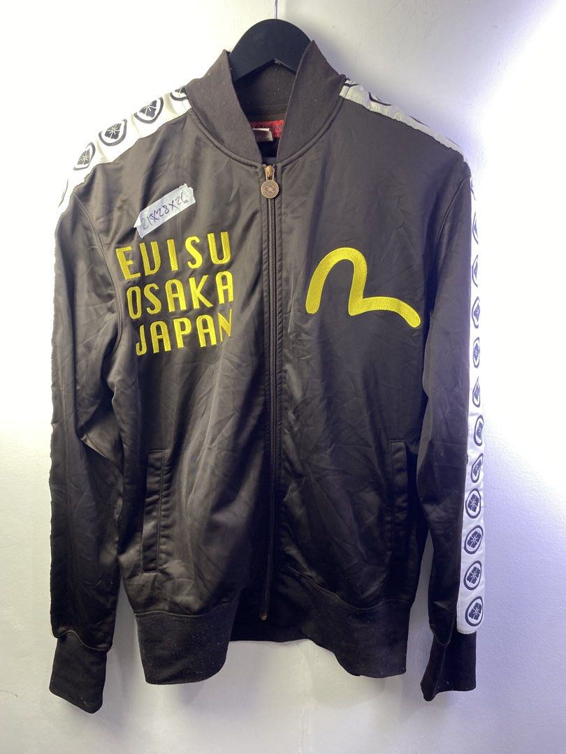 Evisu Osaka Japan Track Jacket (Category: Coats, Jackets and Outerwear) located in Manila. Submitted by declutterpromax (Listing ID 1469002132, Image 1). Description: - Brand: Yamane / Evisu - Color: Black with bold yellow embroidery on the chest - Back Design: Large, iconic Ebisu graphic print - Details: Branded zipper pull, taped sleeves with circular logos, and ribbed collar, cuffs, and hem - Material: 100% polyester (machine washable) - Origi