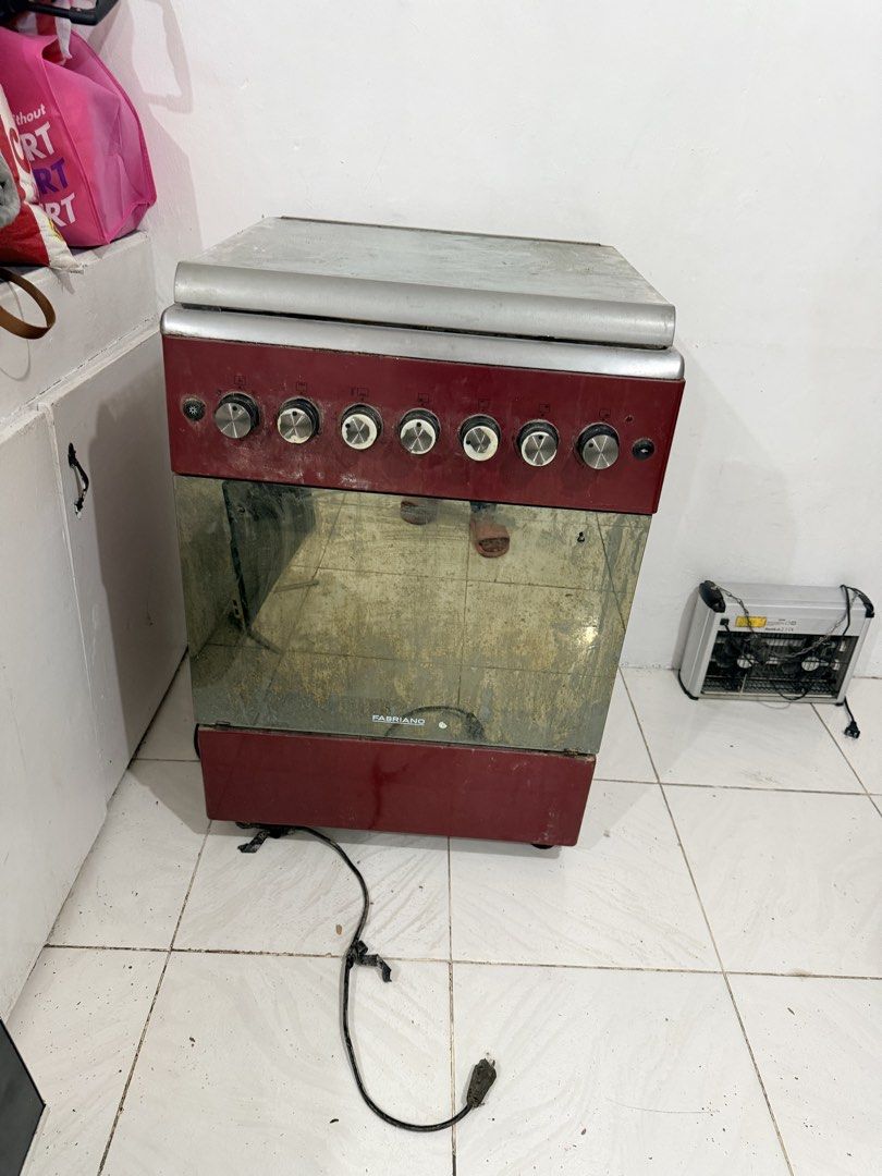 Fabriano Standing Gas Cooker with Oven Red (Category: Cookers) located in Bacoor. Submitted by switcute617 (Listing ID 1469161012, Image 1). Description: - Brand: Fabriano Standing Cooker - Color: Red and Silver - Features: 4 hob burners, electric hotplate, oven compartment, front control knobs, and rear glass splash guard - Condition: Heavy grease, food residue, and rust present across burners, grates, and glass - Note: Needs a thorough deep cle