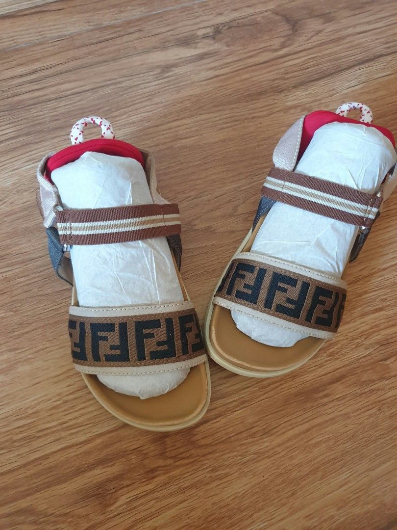 Fendi Kids Sandals (Category: Babies & Kids Fashion) located in Laoag. Submitted by alyssamarie_2918 (Listing ID 1468982462, Image 2). Description: - Brand: Fendi Kids - Design: Iconic brown and black FF logo pattern with a vibrant red heel accent - Size: 30 (Marked on sole) - Origin: Made in Italy - Condition: Brand new, never worn outside, clean soles, still includes original paper stuffing from storage - Features: Adjustable strap for a secure