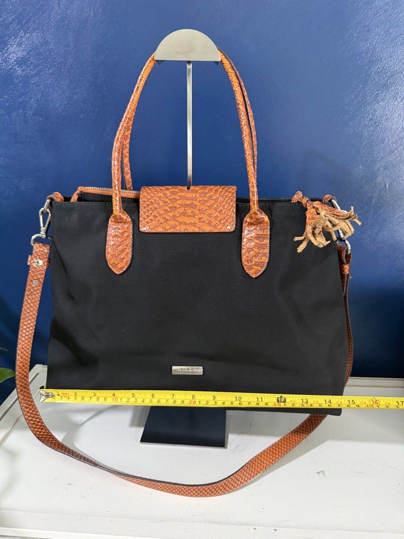 Fino Leatherware Black Canvas Orange Leather Trim (Category: Shoulder Bags) located in Makati City. Submitted by katdestash (Listing ID 1468971467, Image 2). Description: - Material: Durable black canvas/nylon with orange leather trim - Design: Tote bag with flap closure, zip top, and tassel accent - Interior: Light beige fabric lining with zip and slip pockets - Versatility: Includes top carry handles and a detachable shoulder strap - Dimensions