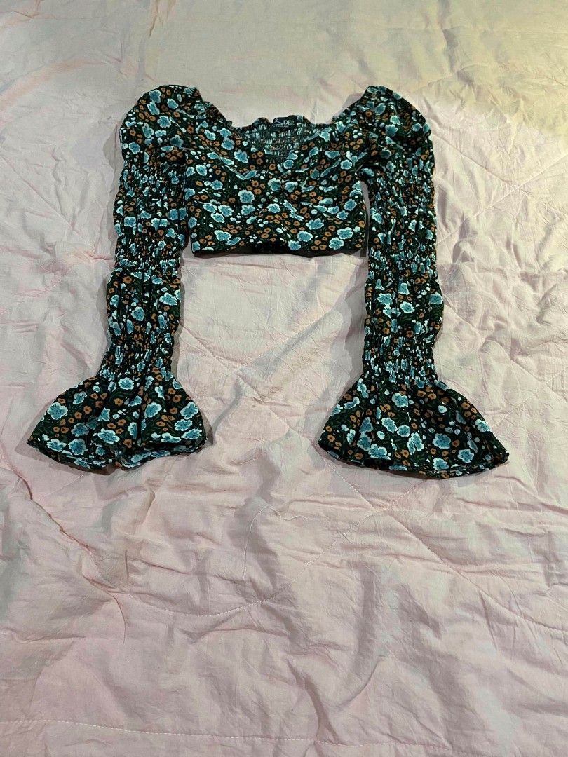 Floral long sleeve croptop (Category: Longsleeves) located in Santa Cruz. Submitted by gelpcz (Listing ID 1468950593, Image 3). Description: - Size: Small - Style: Floral long sleeve crop top with a trendy, cute vibe - Print: Dark background with all-over blue and orange flowers - Details: Smocked bodice and chic square neckline - Sleeves: Dramatic flared bell sleeves with smunching along the arms - Condition: Great addition to your wardrobe!.