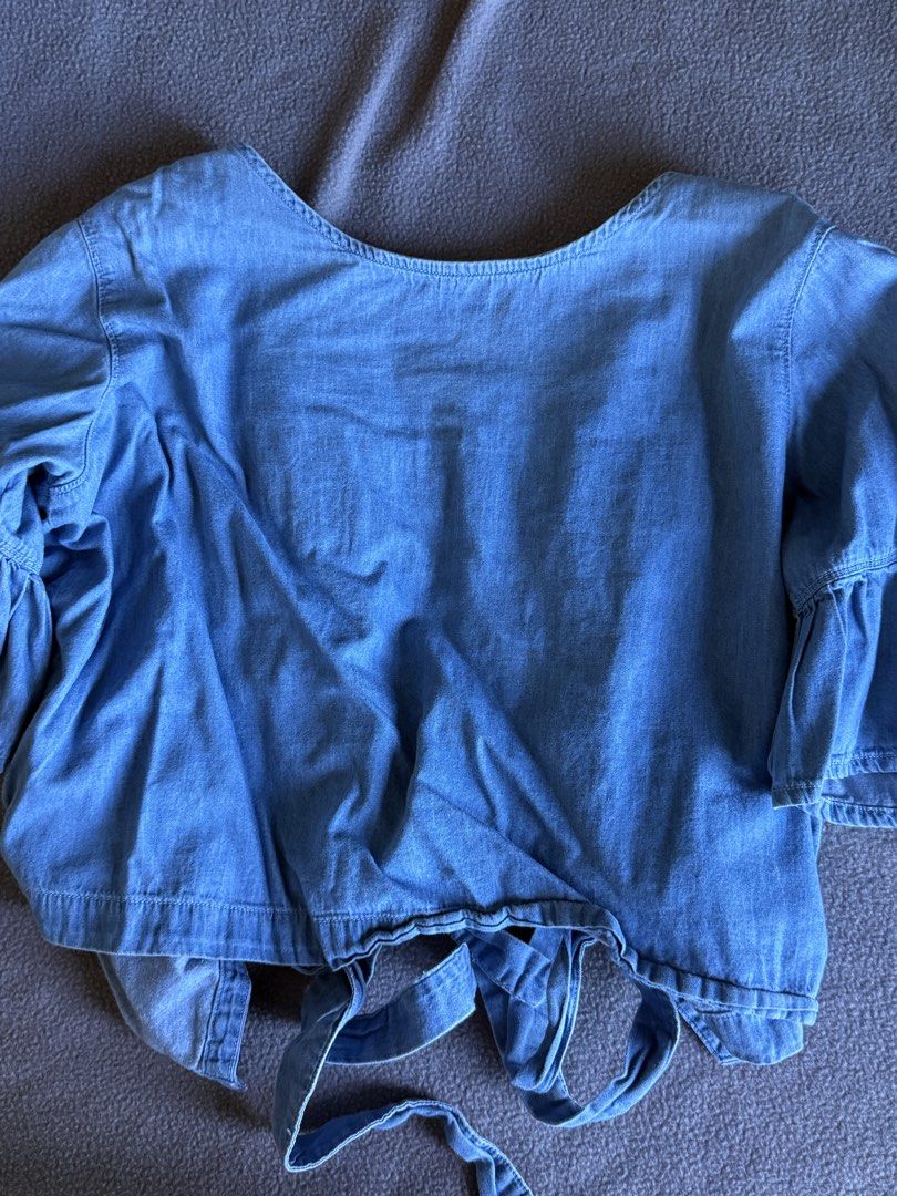 Forme Denim Blue Tie-Back Top Size L (Category: Blouses) located in Pasig City. Submitted by laagn.ph (Listing ID 1469088781, Image 2). Description: - Brand: Forme - Color: Denim Blue - Size: M - Design: Tie-back with multiple bow closures and trendy ruffled bell sleeves - Material: Lightweight chambray, perfect for casual days - Condition: Pre-loved (check label tag for sizing details).