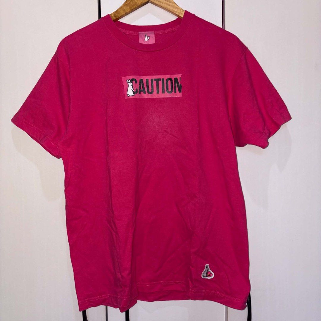FR2 Caution Pink T-Shirt (Category: Tshirts & Polo Shirts ) located in Rosario. Submitted by elyukano2506 (Listing ID 1469021752, Image 1). Description: - Brand: FR2 - Color: Bright Pink - Size: Medium - Material: 100% Cotton - Design: Large CAUTION rabbit graphic on chest, small embroidered rabbit patch near hem - Details: Crew neck, short sleeves, solid pink back, original collar tag and care label - Condition: Excellent / Pre-loved (ready to w