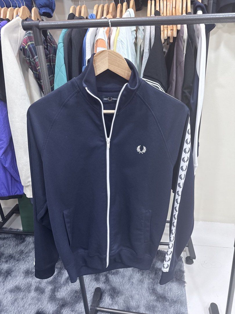 Fred Perry Navy Track Jacket with White Tape Sleeves (Category: Coats, Jackets and Outerwear) located in Quezon City. Submitted by nichole12 (Listing ID 1469111516, Image 1). Description: - Brand: Fred Perry - Color: Navy blue with white accents - Features: Full white zip, iconic white laurel wreath taping on left sleeve, and embroidered white logo on chest - Pockets: Two front slip pockets - Details: Ribbed collar, cuffs, and hem - Style: Classi