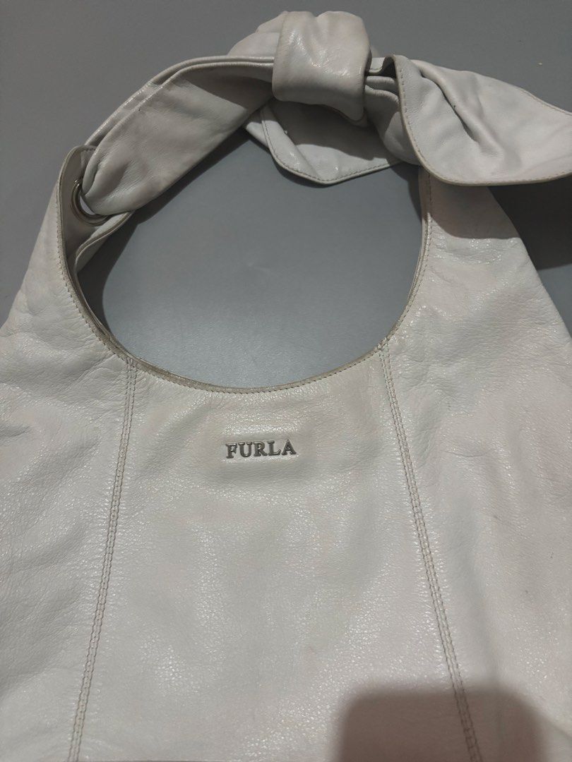 Furla White Leather Shoulder Bag with Bow Detail (Category: Luxury Bags & Wallets) located in Subic. Submitted by thriftpoison (Listing ID 1468935821, Image 2). Description: - Brand: Furla - Material: Soft pebbled white leather - Hardware: Silver-tone with front brand lettering - Design details: Vertical stitched panels and a unique knotted bow accent on the strap - Condition: Shows minor discoloration and wear marks along the top edge and handle