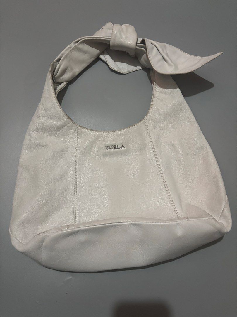 Furla White Leather Shoulder Bag with Bow Detail (Category: Luxury Bags & Wallets) located in Subic. Submitted by thriftpoison (Listing ID 1468935821, Image 1). Description: - Brand: Furla - Material: Soft pebbled white leather - Hardware: Silver-tone with front brand lettering - Design details: Vertical stitched panels and a unique knotted bow accent on the strap - Condition: Shows minor discoloration and wear marks along the top edge and handle