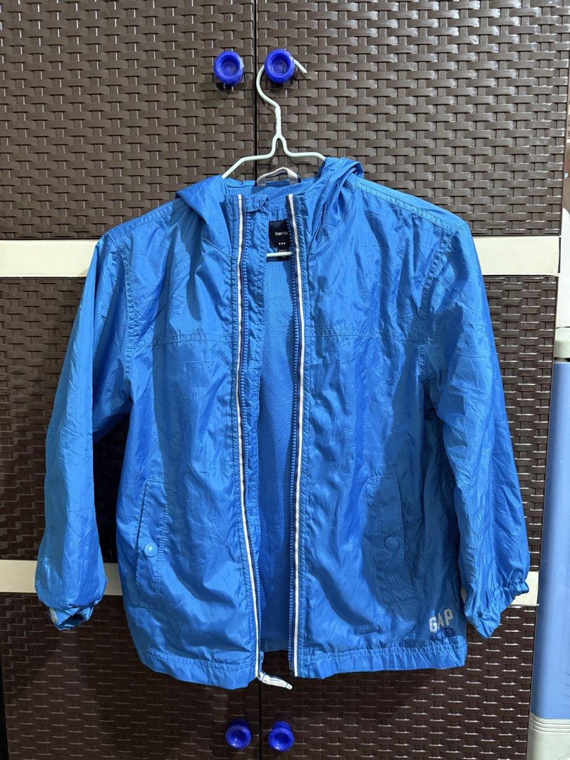 GapKids Blue Windbreaker Jacket Size 130 (Category: Tshirts & Polo Shirts ) located in Manila. Submitted by vastwind-676c (Listing ID 1468957087, Image 1). Description: - Brand: GapKids - Size: 130 - Color: Bright blue - Material: Lightweight with breathable mesh lining - Features: Full zip closure with white trim, attached hood, front pockets, and Gap 1969 logo near the hem - Origin: Made in Vietnam - Condition: Great for outdoor activities and 