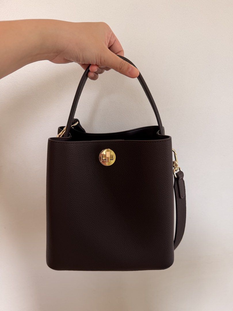 Genuine Leather Bucket Bag (Category: Shoulder Bags) located in Marikina City. Submitted by melsellstuff (Listing ID 1468947377, Image 2). Description: - Material: Dark brown textured leather with gold-tone hardware - Closure: Secure front flap with turn-lock closure - Straps: Includes a matching top handle and a detachable, adjustable shoulder strap - Interior: Dark lining with a zipped pocket; deep space for daily essentials - Condition: New, n