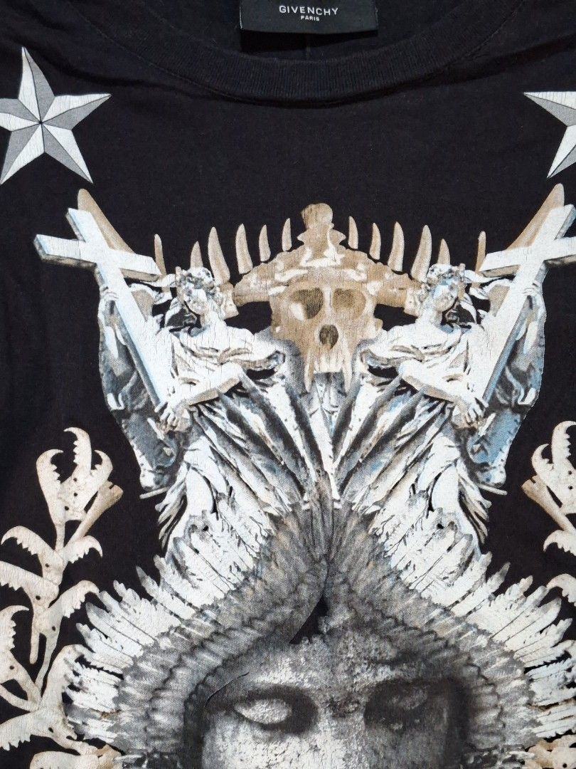 Givenchy Paris Black Graphic Tee (Category: Shirts) located in Baguio. Submitted by restyrille77846 (Listing ID 1469095198, Image 3). Description: - 100% Authentic Givenchy Paris black t-shirt - Striking front graphic print featuring winged face, skulls, stars, and cross details - Classic crew neck, short sleeves, and standard fit - Premium cotton jersey fabric for ultimate comfort - Interior brand tag intact - Care: Machine wash inside out - Con