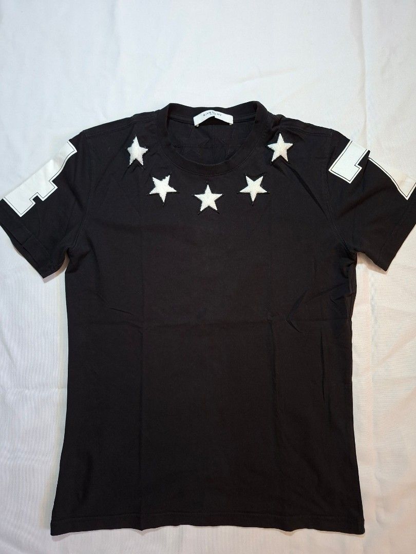 Givenchy Paris Star Patch Short Sleeve T-Shirt Black (Category: Shirts) located in Baguio. Submitted by restyrille77846 (Listing ID 1469069938, Image 1). Description: - Brand: Givenchy Paris - Color: Black with white accents - Material: Premium quality cotton - Design: White star patches around the neckline - Details: Number 1 and 4 prints on the short sleeves - Fit: Classic crew neck, ideal for streetwear - Condition: Great designer piece.