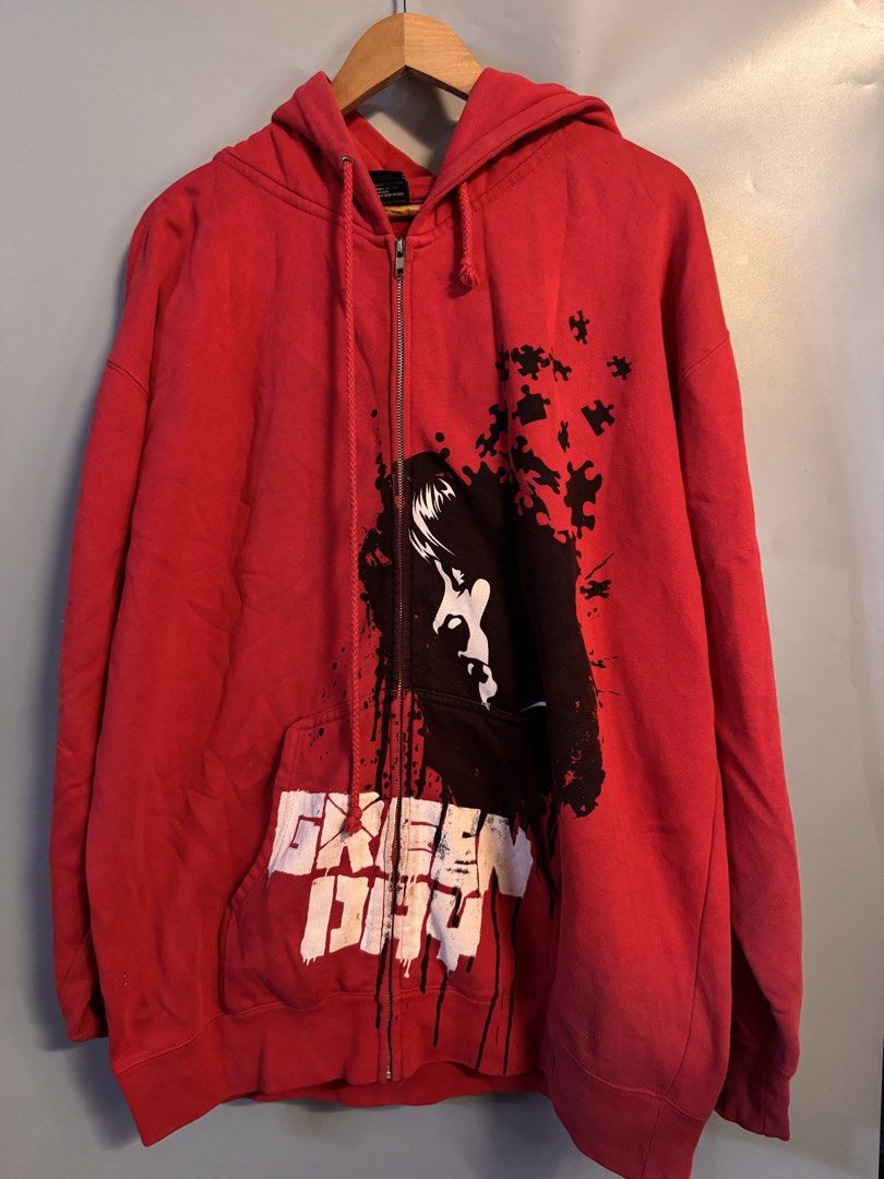 Green Day Red Zip-Up Hoodie (Category: Hoodies) located in Alaminos. Submitted by outfitcheck.ph (Listing ID 1469102483, Image 1). Description: - Brand/Style: Official Green Day band merch red zip-up hoodie - Size: XL - Design: Striking black and white graphic portrait with puzzle piece accents and distressed band lettering at the pocket - Material: 80% cotton, 20% polyester - Features: Adjustable drawstring hood and full front metal zipper - Con