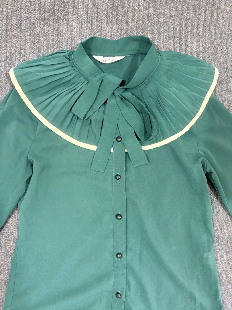 Green pleated collar long sleeve button down blouse (Category: Longsleeves) located in Quezon City. Submitted by fast.closetfinds (Listing ID 1469018432, Image 2). Description: - Color: Emerald green - Material: Lightweight, slightly sheer chiffon - Details: Large pleated contrast collar, matching neck tie, dark front buttons - Sleeve: Long sleeve - Condition: Clean, worn a few times.