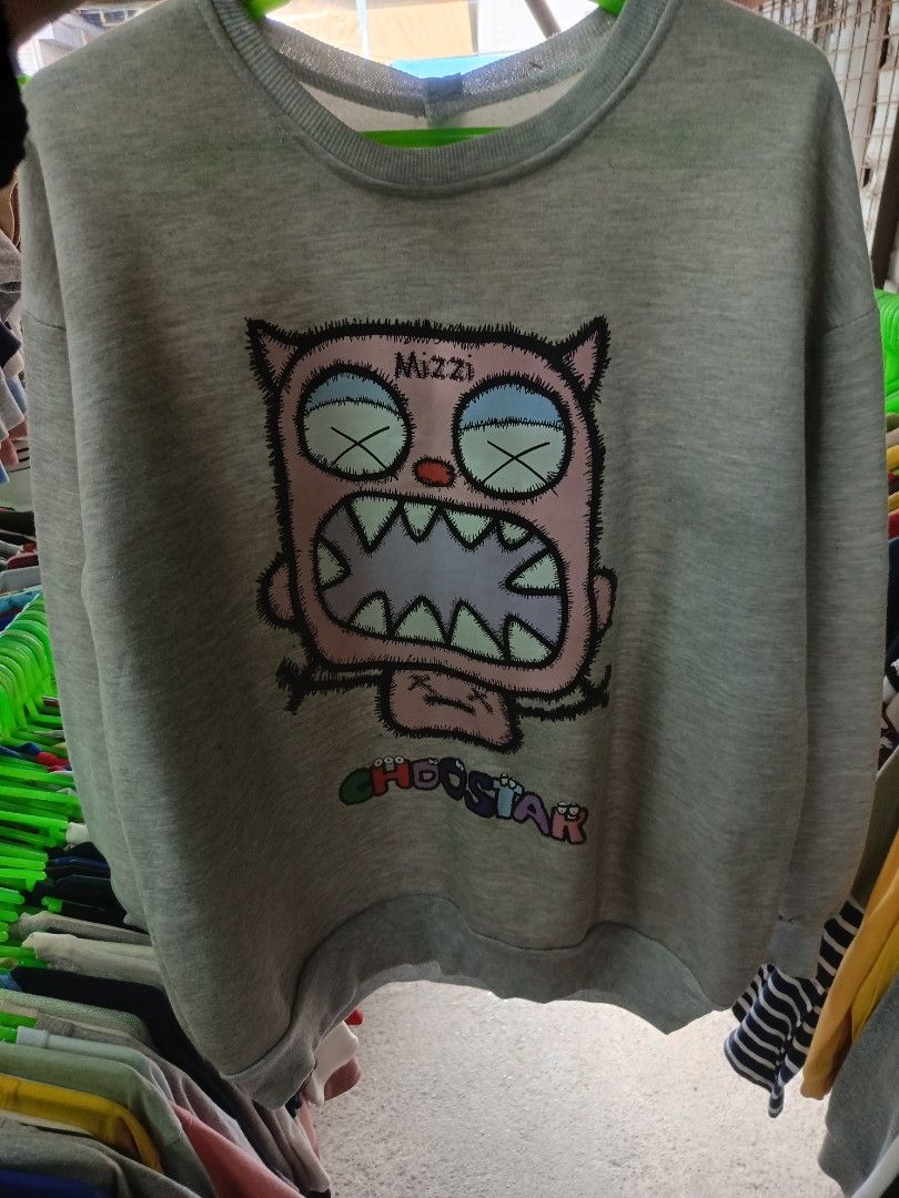 Grey Crewneck Sweatshirt with Graphic Print (Category: Coats, Jackets and Outerwear) located in Cabatuan. Submitted by penthegreat (Listing ID 1469111125, Image 1). Description: No tags/washtags - Colour: Grey - Fit: Relaxed fit with soft cotton-blend fabric - Design: Large pink monster graphic on chest with 'Mizzi' and colourful 'CHOOSSTAR' lettering - Details: Ribbed collar, cuffs, and hem for added comfort - Condition: Brand new and ready to w