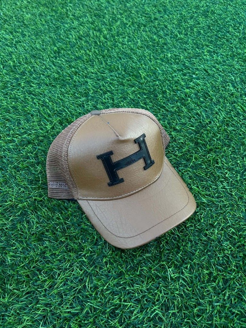 Hermes Brown Leather H Logo Trucker Hat Cap (Category: Caps & Hats) located in Pasig City. Submitted by paulclzdo (Listing ID 1469064972, Image 3). Description: - Style: Classic trucker hat - Front: Brown faux leather with black embroidered H logo - Back: Breathable mesh with adjustable snapback closure - Interior: Hermès branded sweatband taping and care tag - Condition: Great piece to elevate your daily outfits - Shipping or meetups available a