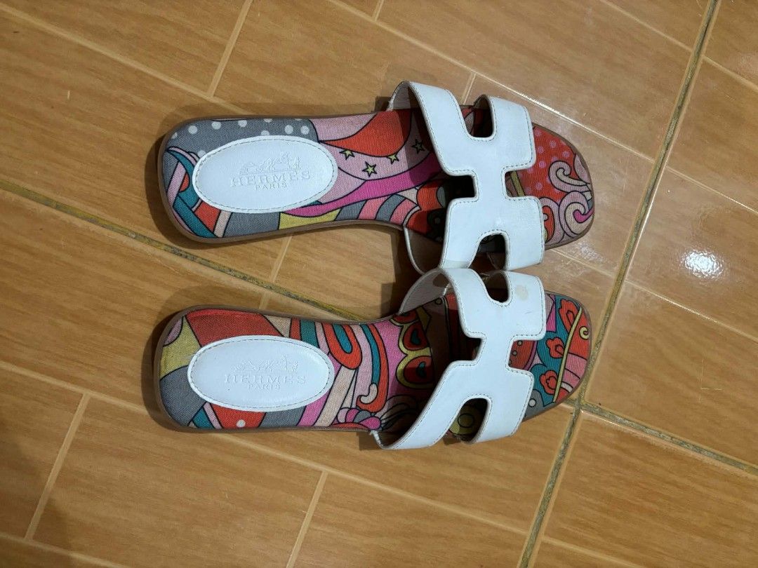 Hermès Oran Printed Canvas Sandals Size 37 (Category: Flats & Sandals) located in Paranaque City. Submitted by poego (Listing ID 1468955024, Image 1). Description: - Brand: Hermès - Style: Flat sandals with H-cut straps - Color/Material: White leather and multicolored patterned canvas footbed - Size: 37 (stamped on soles) - Origin: Made in Italy (Code: H-359 inside strap) - Condition: Visible wear and scuff marks on soles, clean inner branding.