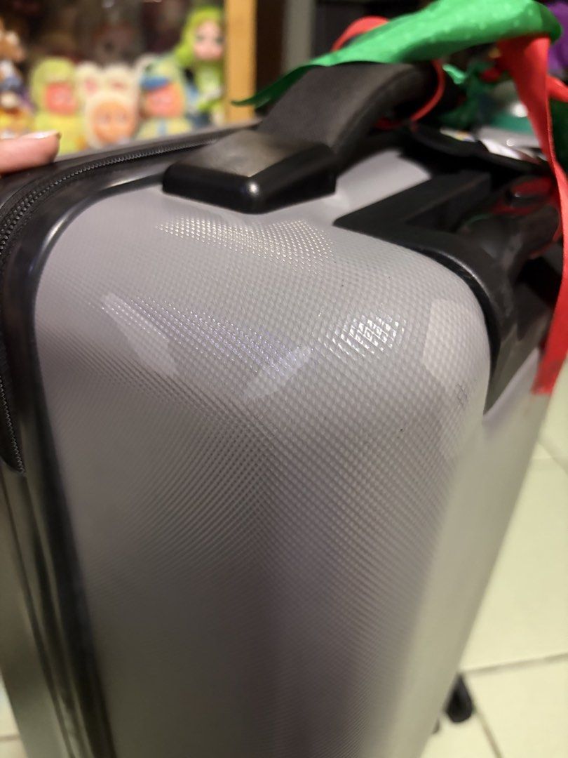 Herschel Grey Hardside Spinner Luggage (Category: Luggage) located in Makati City. Submitted by nicluttering (Listing ID 1469002748, Image 3). Description: - Brand: Herschel - Color: Grey hardside with vertical ribbed texture - Mobility: 4 smooth-rolling spinner wheels & telescoping pull handle - Security: Built-in side combination lock - Extras: Sturdy top handle with a decorative green and red ribbon, plus front rubber logo patch - Condition: N