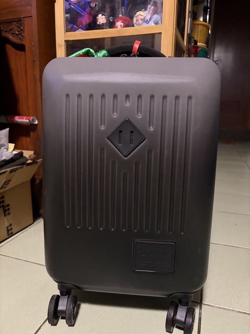 Herschel Grey Hardside Spinner Luggage (Category: Luggage) located in Makati City. Submitted by nicluttering (Listing ID 1469002748, Image 1). Description: - Brand: Herschel - Color: Grey hardside with vertical ribbed texture - Mobility: 4 smooth-rolling spinner wheels & telescoping pull handle - Security: Built-in side combination lock - Extras: Sturdy top handle with a decorative green and red ribbon, plus front rubber logo patch - Condition: N