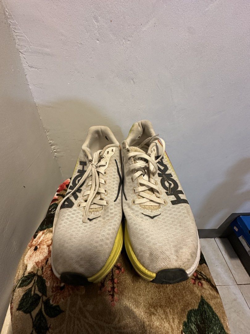 Hoka Running Shoes (Category: Sneakers) located in Manila. Submitted by hanso__oo (Listing ID 1469118513, Image 3). Description: - Brand: Hoka Running Shoes - Colorway: White upper with bold yellow and red midsoles - Design: Large Hoka logo on the side, traditional lace-up, breathable mesh material - Condition: Signs of use with noticeable dirt on soles and fabric from regular runs - Performance: Cushioning is still very plush with plenty of mile