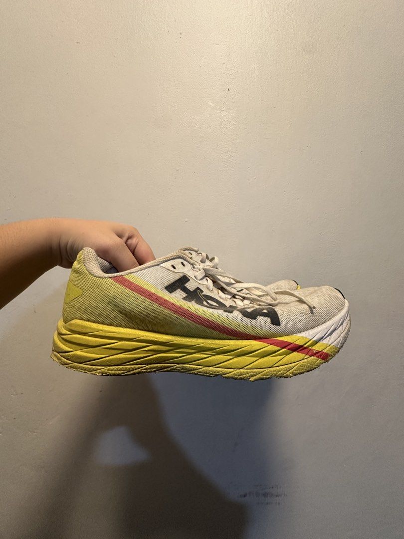 Hoka Running Shoes (Category: Sneakers) located in Manila. Submitted by hanso__oo (Listing ID 1469118513, Image 1). Description: - Brand: Hoka Running Shoes - Colorway: White upper with bold yellow and red midsoles - Design: Large Hoka logo on the side, traditional lace-up, breathable mesh material - Condition: Signs of use with noticeable dirt on soles and fabric from regular runs - Performance: Cushioning is still very plush with plenty of mile