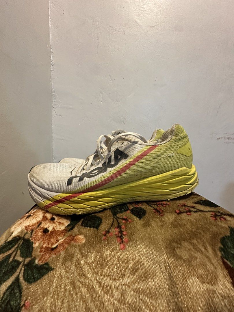 Hoka Running Shoes (Category: Sneakers) located in Manila. Submitted by hanso__oo (Listing ID 1469118513, Image 2). Description: - Brand: Hoka Running Shoes - Colorway: White upper with bold yellow and red midsoles - Design: Large Hoka logo on the side, traditional lace-up, breathable mesh material - Condition: Signs of use with noticeable dirt on soles and fabric from regular runs - Performance: Cushioning is still very plush with plenty of mile