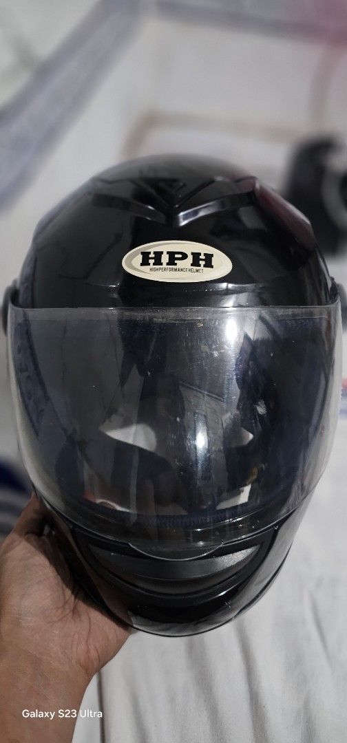 HPH High Performance Black Motorcycle Helmet (Category: Bicycles) located in Tarlac. Submitted by chiefnaticz2020 (Listing ID 1469128375, Image 1). Description: - Brand: HPH - Type: Full face motorcycle helmet - Color: Glossy black with side sticker - Visor: Clear with standard adjustment - Interior: Comfortable dark blue padding - Closure: Quick-release buckle strap (note: minor rust on metal hardware).