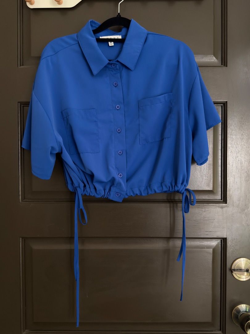 HYFVE Royal Blue Button Up Crop Blouse (Category: Blouses) located in Calamba. Submitted by prongsiepoo (Listing ID 1469079736, Image 1). Description: - Brand: Hyfve - Color: Bright royal blue - Fit: Relaxed fit through the body - Details: Collared neck, short sleeves, and two front chest pockets - Feature: Adjustable drawstring hem for waist cinching - Material: Lightweight fabric.