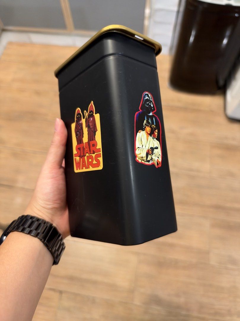 IKEA Storage Tin (Category: Western Merchandise) located in Manila. Submitted by garagesalebykoda (Listing ID 1468988184, Image 3). Description: - Authentic IKEA black metal storage tin with a stylish gold lid - Used it for coffee beans - Decorated with custom Star Wars stickers featuring Jawas, Grogu in a coffee cup, and classic character art - Features standard IKEA branding on the bottom - Perfect for organizing stationery, small trinkets, or 